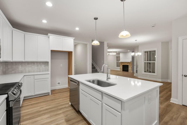 kitchen with sink, decorative backsplash, an island with sink, white cabinetry, and stainless steel appliances