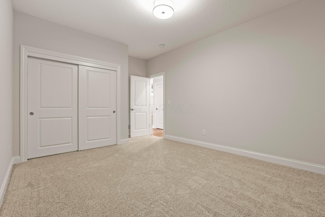 unfurnished bedroom featuring light carpet and a closet