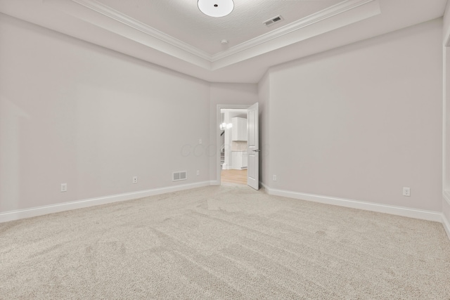 carpeted spare room with ornamental molding and a tray ceiling