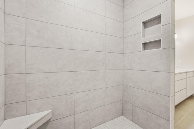 bathroom featuring a tile shower, tile patterned flooring, and vanity