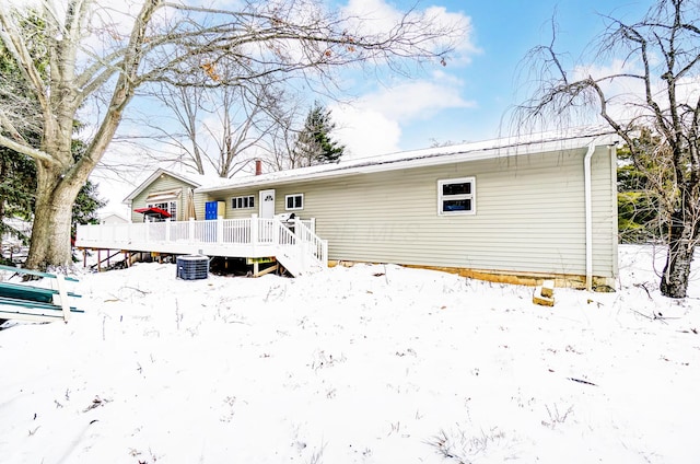 snow covered rear of property with a deck