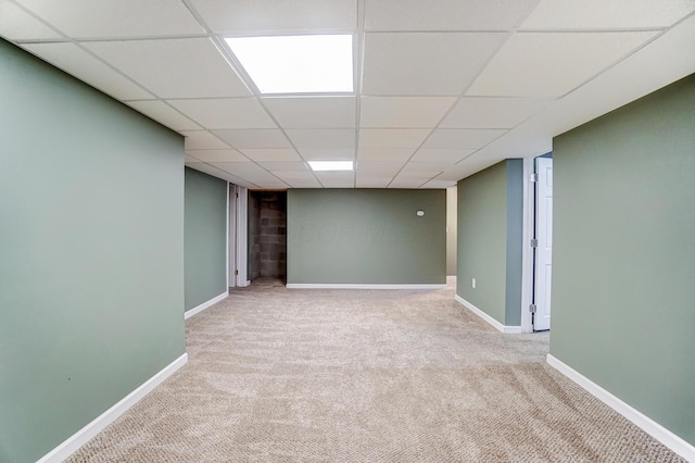 basement featuring a paneled ceiling and light colored carpet