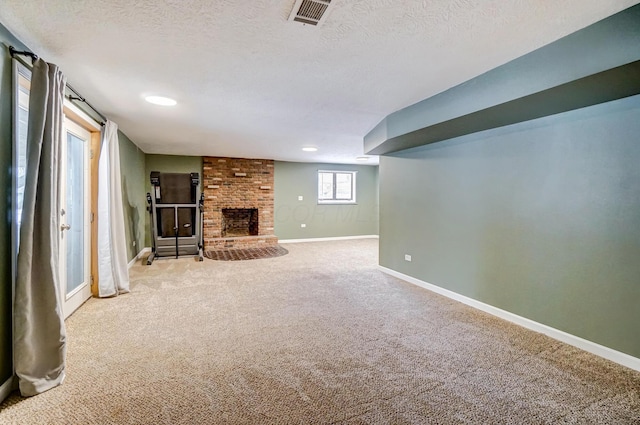 unfurnished living room with carpet, a textured ceiling, and a brick fireplace