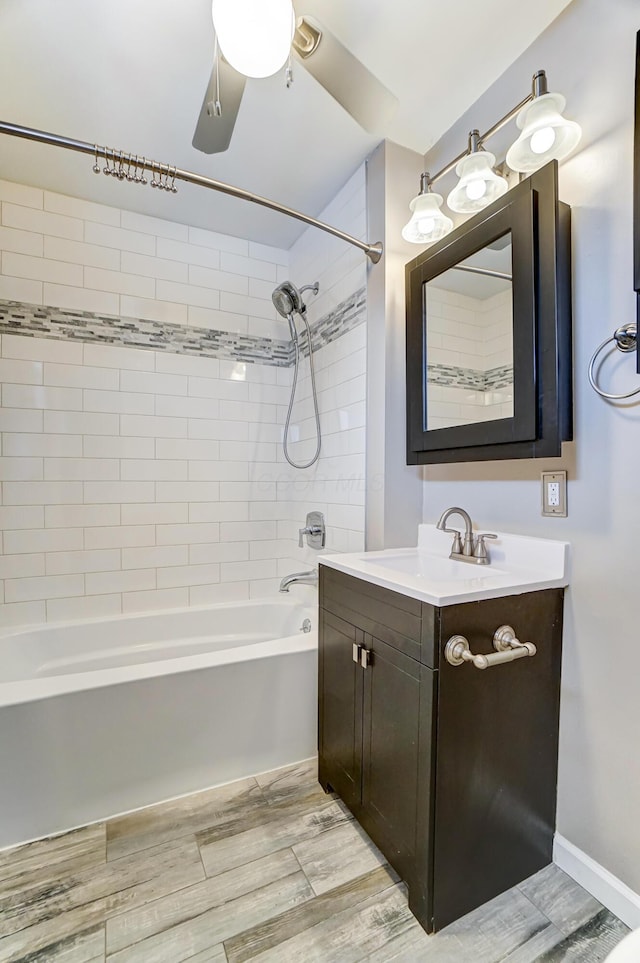 bathroom with ceiling fan, vanity, and tiled shower / bath