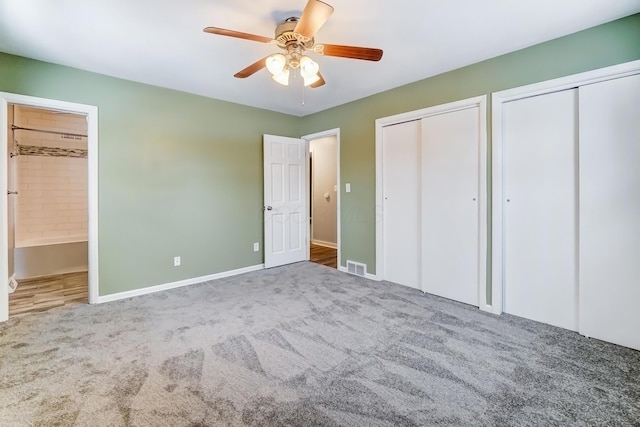 unfurnished bedroom featuring connected bathroom, multiple closets, ceiling fan, and carpet