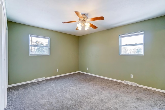 unfurnished room with a wealth of natural light, carpet floors, and ceiling fan