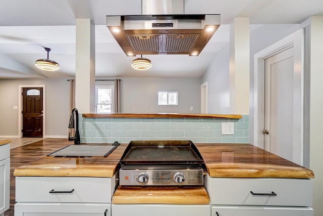 kitchen featuring island exhaust hood, wood counters, backsplash, sink, and white cabinetry