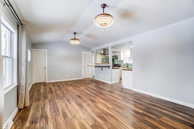 unfurnished living room featuring wood-type flooring, lofted ceiling, and a wealth of natural light