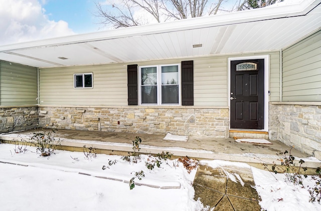 snow covered property entrance with a porch