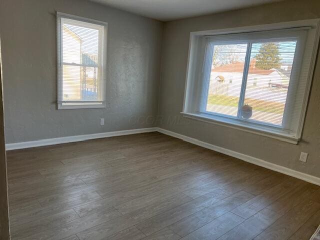 empty room featuring plenty of natural light and dark hardwood / wood-style floors