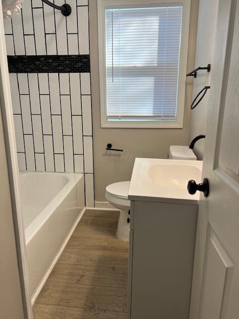 full bathroom featuring tiled shower / bath, vanity, toilet, and hardwood / wood-style floors