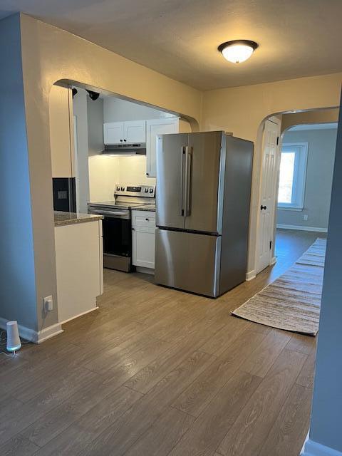 kitchen with white cabinetry, appliances with stainless steel finishes, and hardwood / wood-style floors