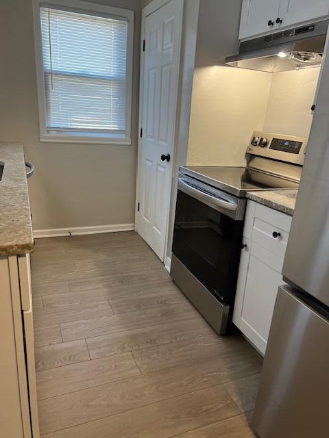 kitchen with electric range, white cabinets, and light wood-type flooring