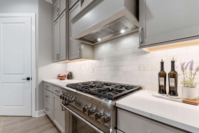 1474 Dogwood Loop, Powell, OH 43065 - kitchen with gray cabinetry, light countertops, premium range hood, and high end stainless steel range oven