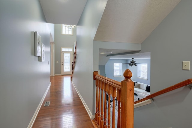 hall with hardwood / wood-style floors, a high ceiling, a wealth of natural light, and a chandelier