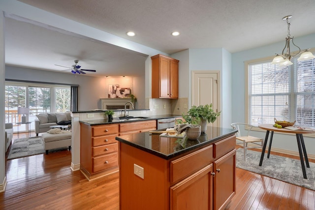 kitchen with ceiling fan with notable chandelier, a center island, a healthy amount of sunlight, and hanging light fixtures