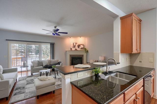 kitchen featuring dark hardwood / wood-style flooring, backsplash, ceiling fan, sink, and dark stone countertops