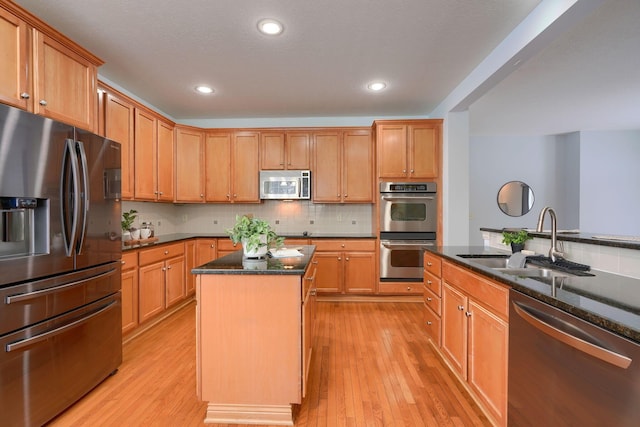 kitchen with a center island, backsplash, dark stone counters, sink, and stainless steel appliances