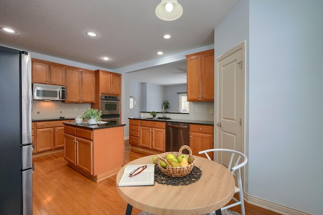 kitchen with a center island, sink, tasteful backsplash, light hardwood / wood-style floors, and stainless steel appliances