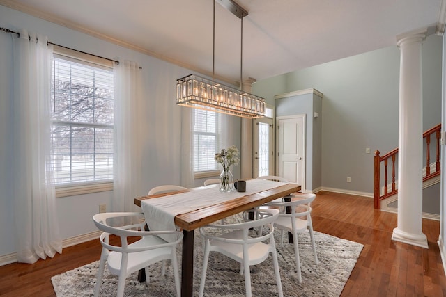 dining space with wood-type flooring, decorative columns, and a wealth of natural light