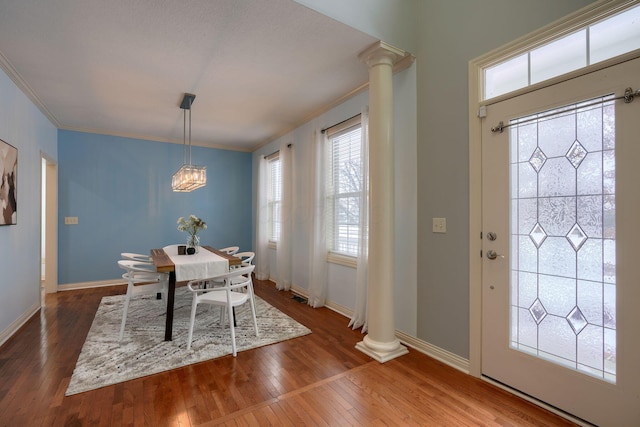 dining space with hardwood / wood-style flooring, ornate columns, ornamental molding, and a chandelier