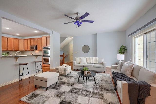 living room featuring ceiling fan, wood-type flooring, and sink