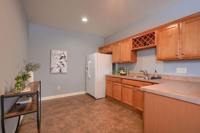 kitchen featuring white fridge with ice dispenser and sink