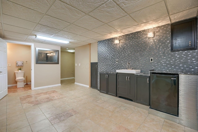 kitchen featuring stone counters, sink, a drop ceiling, and fridge