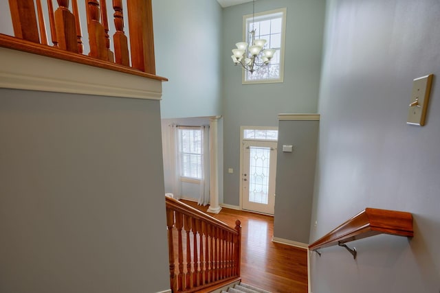 entrance foyer featuring hardwood / wood-style floors, a high ceiling, a healthy amount of sunlight, and a notable chandelier