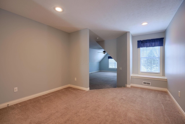 additional living space with carpet flooring, a textured ceiling, ceiling fan, and lofted ceiling