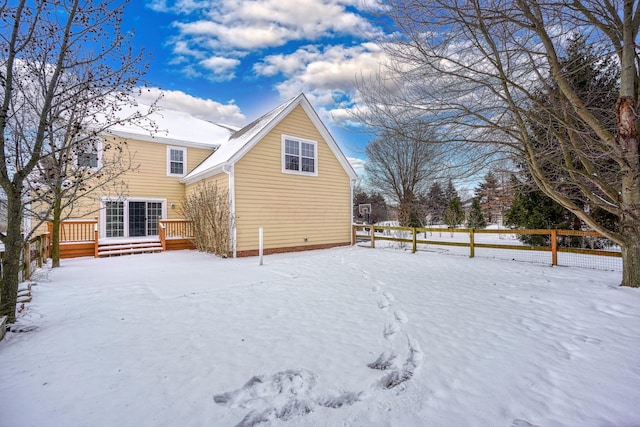 snow covered house with a wooden deck