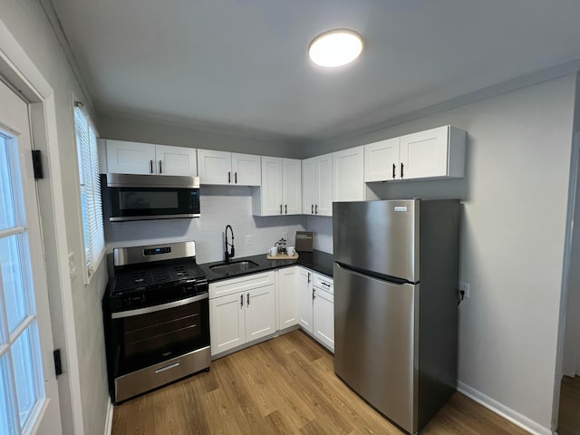 kitchen with white cabinets, sink, stainless steel appliances, and light hardwood / wood-style flooring