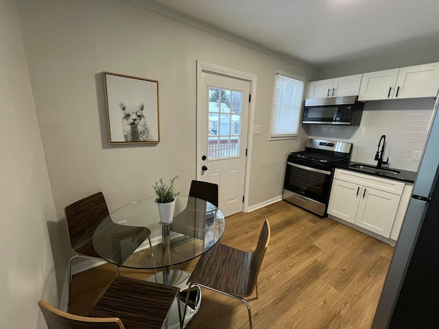 kitchen featuring light wood-type flooring, white cabinetry, sink, and stainless steel range