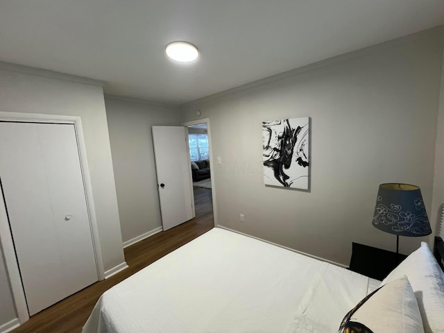 bedroom featuring ornamental molding, dark wood-type flooring, and a closet