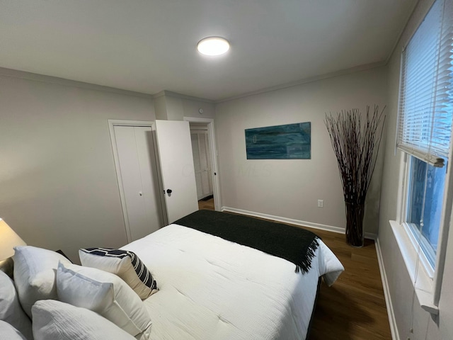 bedroom featuring dark hardwood / wood-style floors, multiple windows, crown molding, and a closet