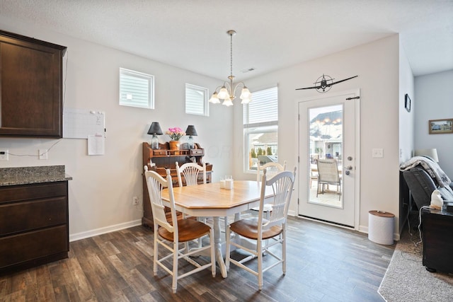 dining space with dark hardwood / wood-style flooring and a notable chandelier