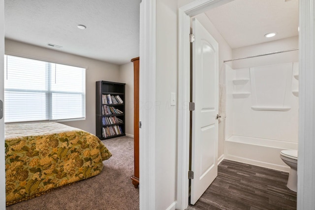 bedroom featuring ensuite bath and dark carpet