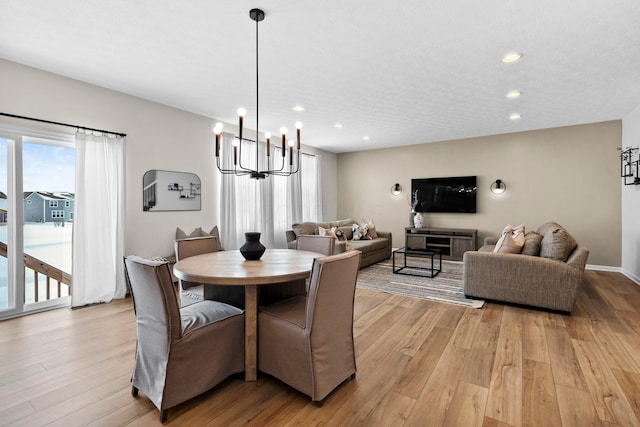 dining space with light wood-type flooring and an inviting chandelier