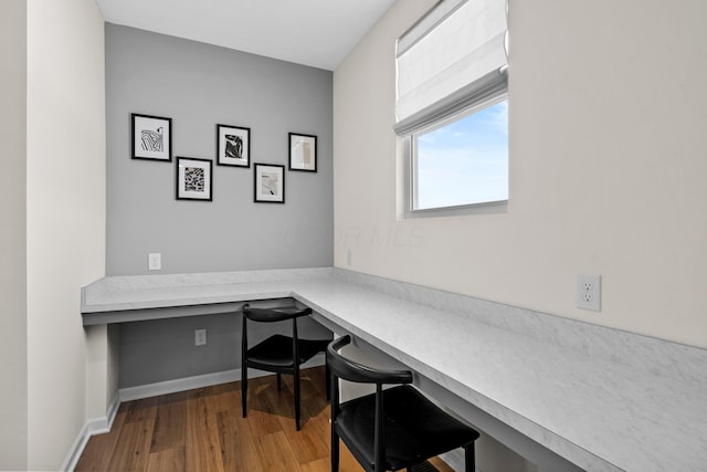 office with wood-type flooring and built in desk