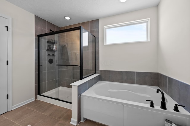 bathroom with a textured ceiling and shower with separate bathtub