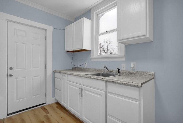 kitchen with ornamental molding, white cabinetry, sink, and light hardwood / wood-style flooring