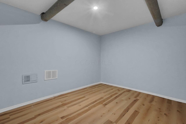 spare room featuring beam ceiling and wood-type flooring