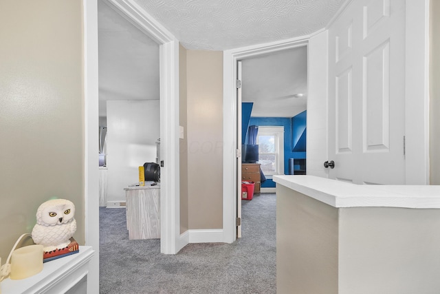 hallway featuring carpet flooring and a textured ceiling