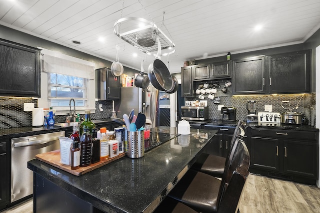 kitchen with a center island, a kitchen breakfast bar, tasteful backsplash, light hardwood / wood-style floors, and appliances with stainless steel finishes