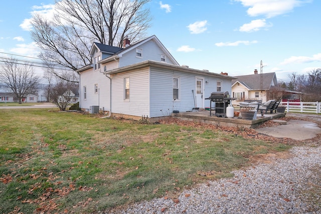 rear view of house featuring central air condition unit, a patio area, and a lawn