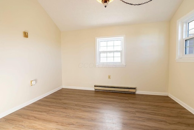 spare room with hardwood / wood-style floors, lofted ceiling, and a baseboard heating unit