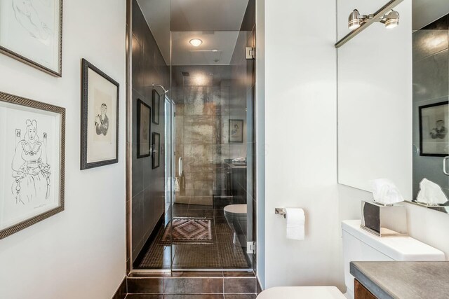 bathroom featuring vanity, a shower with shower door, and toilet