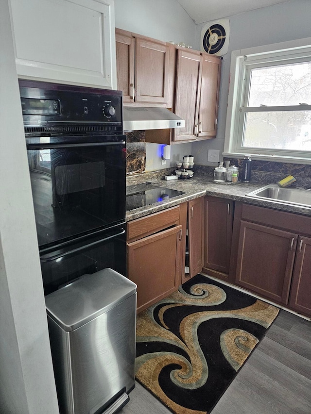 kitchen featuring black appliances, sink, dark wood-type flooring, and vaulted ceiling