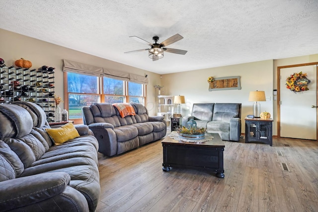 living room with ceiling fan, hardwood / wood-style floors, and a textured ceiling