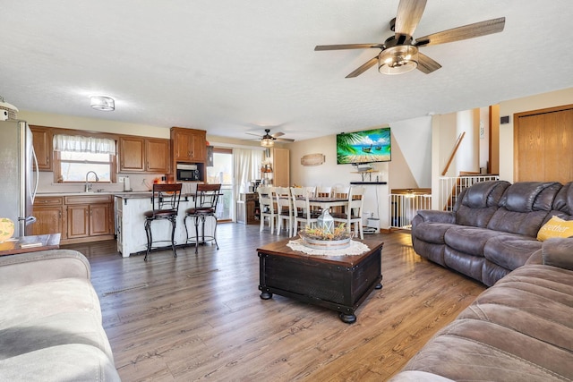 living room with a wealth of natural light, ceiling fan, a textured ceiling, and light wood-type flooring